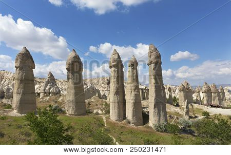Rural Landscape In The Valley Of Love, Cappadocia. Large Phallic Rock Formations Against The Blue Su