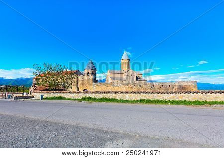 Panorama View Of Alaverdi Orthodox Monastery In Kakhetia Region In Georgia And Snow Peaks Of Caucasu