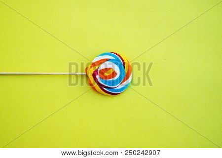Colorful Hard Candy Lollipop On Yellow Pastel Background. Rainbow Sweet Pattern On Stick Flying Arou