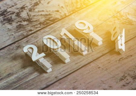 New Year 2019 Concept. Clothpin With Number 2019 On Wooden Background With Sun Flare.