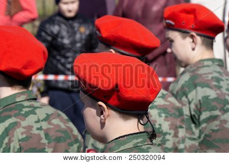 Military Kid Wearing Red Beret Next To A Russian Flag Back View. Patriotic Young Boy In A Uniform At