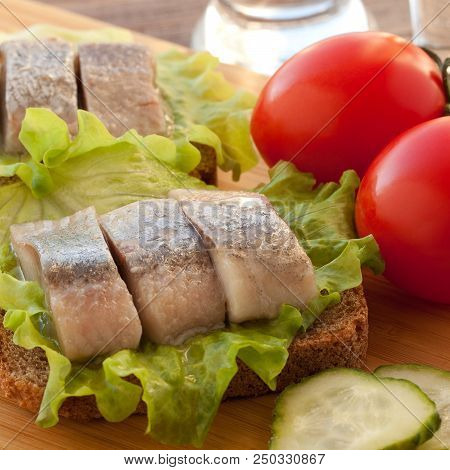 Two Sandwiches Of Rye Bread And Herring With Lettuce, Tomatoes And Cucumber