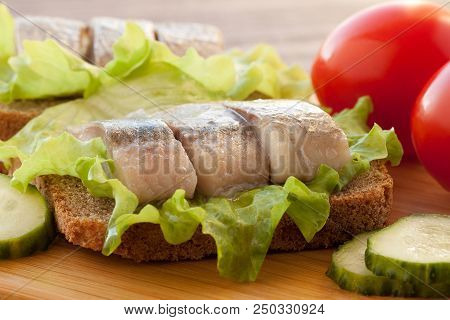 Two Sandwiches Of Rye Bread And Herring With Lettuce, Tomatoes And Cucumber