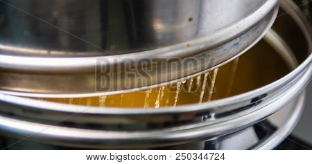 Strain The Poured Honey Through A Sieve. How To Harvest Honey. Filtering Raw Honey.