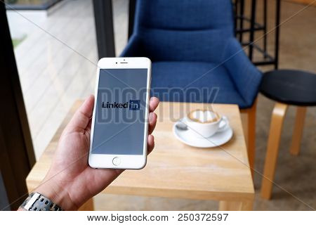 A Man Sit In Cafe Holding Mobile With Linked Screen