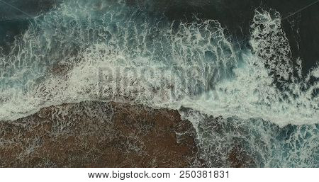 Aerial Photography. A Foamy Large Sea Wave Is Broken Against The Rocks.