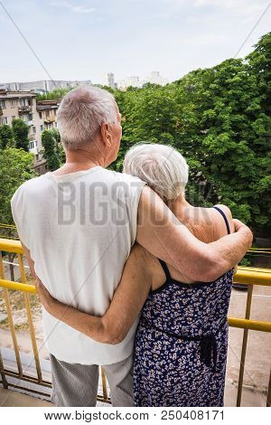 Senior Couple Standing Oustide At Balccony At Home And Looking Away