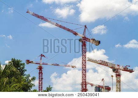 Construction Cranes, Tower Cranes Against The Blue Sky With Clouds