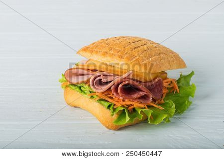 Pressed And Toasted Double Panini With Ham And Cheese Served On Sandwich Paper On A Wooden Table