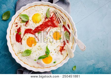 Baked Eggs Shakshouka With Tomato Sauce, Herbs And Fresh Basil In Baked Form On Blue Table. Ready Fo