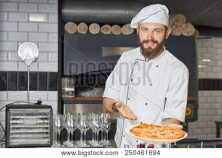 Happy Pizzaiolo Demonstrating Fresh Baked Delicious Pizza.