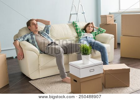 Young Cople Having Rest Between Boxes On Sofa While Moving In A New Apartment