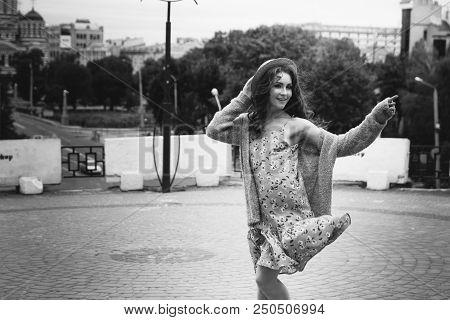 A Beautiful Girl In A Hat, Keeps The Hair From The Wind. Sits On Scraps. Walk Around The City. Portr