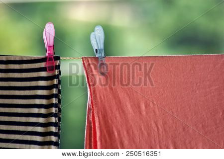 Two Clothespins And Laundry On Clothesline. Two Plastic Colorful Clothespins And Laundry On Clothesl