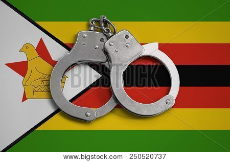 Zimbabwe Flag  And Police Handcuffs. The Concept Of Observance Of The Law In The Country And Protect
