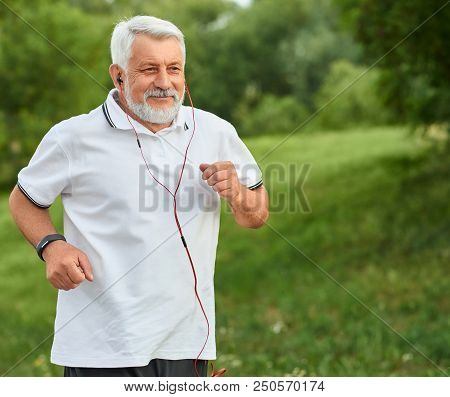 Positive Running Old Man In Green City Park. Smiling, Feeling Good. Sport Lifestyle. Wearing Classic