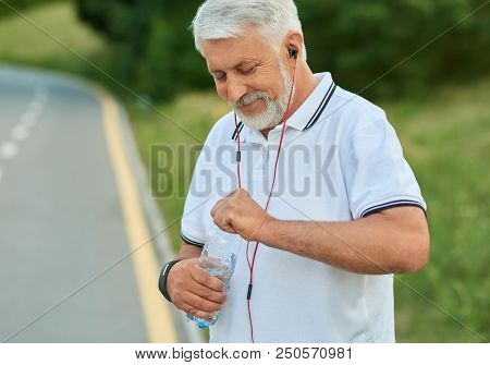 White-heared Senior Man Opening Water Bottle During Scamper. Keeping Body Fit, Muscular, Strong. Mai
