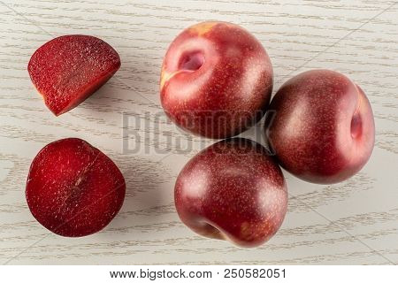 Group Of Three Whole One Half One Slice Of Fresh Pluot Interspecific Plums Variety Flatlay On Grey W