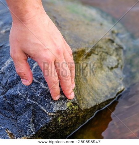Hand Laying Stone On Stacking Stones On The River Bank. The Stones Are Stacked On The Shore. On The 