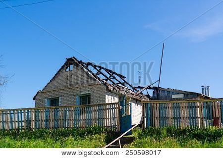 One Ramshackle Old Unfinished Wooden House Against Blue Sky. Reconstruction Of The Old Building