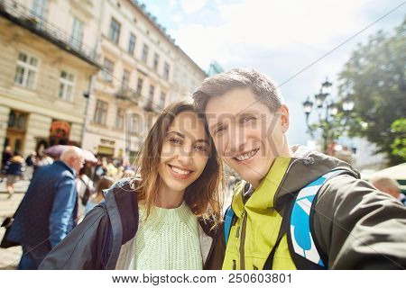 Happy Young Enamored Couple Of Tourists Walking On The Center Of The City And Makes Selfie, Lviv, Uk