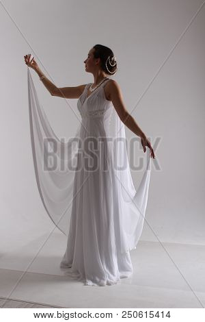 Girl In White With Her Hands Up. The Bride In A Dress In Greek Style. Brunette In Pearl Jewelry. The