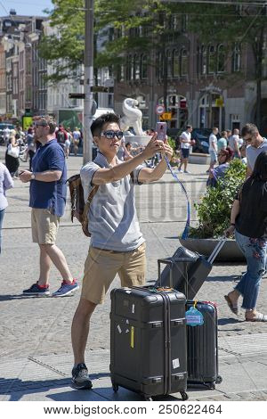 Amsterdam, Netherlands - July 02, 2018: Tourist From China Makes Selfy In The Central Dam Square In 