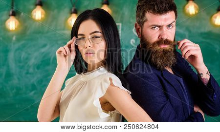 Man With Beard And Teacher In Eyeglasses Stand Back To Back, Chalkboard On Background. Lady And Hips