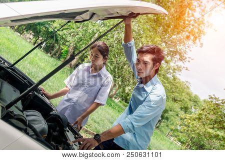 A Woman And Man Leaning Over The Hood Of Broke Down Car.