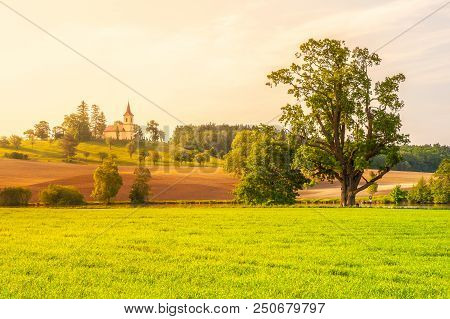 Small Church In The Middle Of Lush Green Spring Landscape On Sunny Day. St. Peter And Pauls Church A