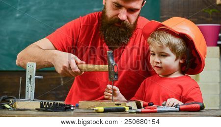 Workshop And Handyman Concept. Father, Parent With Beard Teaching Little Son To Use Hobnails And Ham
