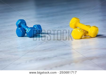Colorfull Modern Dumbbells In The Foreground On A Wooden White Floor