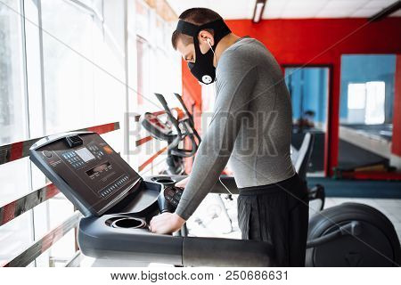 Man Resting Before The Next Race, Doing Sports, In A Training Mask For Breathing On The Treadmill, M