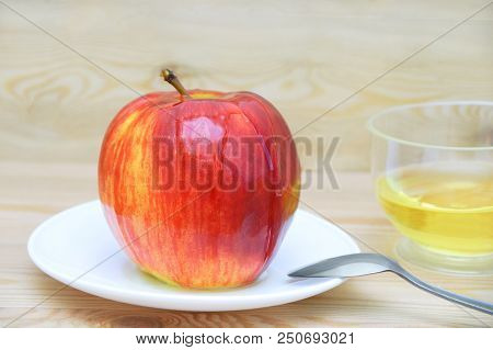 Apple On A White Plate With A Spoon Peppered With Honey On A Wooden Background