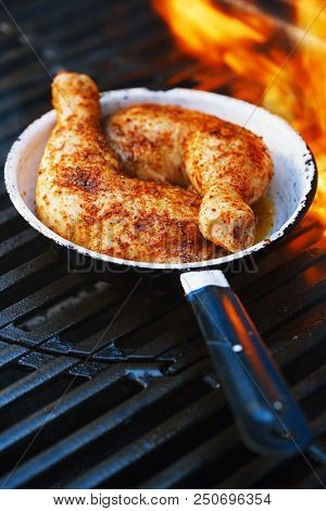 chicken legs spiced by special spice blend on bbq grill with flame