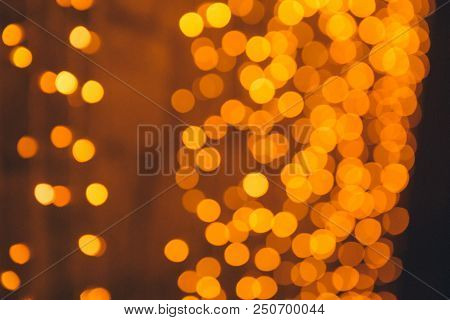 Many Blurred Small Electric Bulbs On A Wall. Yellow Blurred Lights. Wall Of Christmas Lights