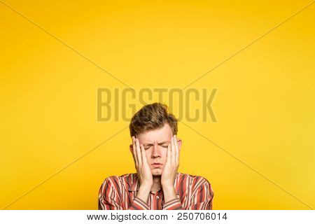 Sad Rueful Depressed Cheerless Man Covering His Face In Hands. Portrait Of A Young Guy On Yellow Bac