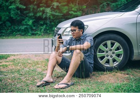 Young Asian Handsome Man Sitting On The Floor By The Broken Down Car And Waiting For Help With Strai