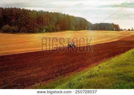 Blue Tractor In The Solar Field Summer And Autumn. Harvesting On The Sun Field