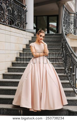 Elegant Lady Satnd On Stairs In Front Of Restaurant.