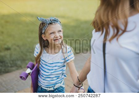 Blue-eyed Girl. Cute Blue-eyed Girl Wearing Striped Hair Band Looking At Her Mother While Walking To