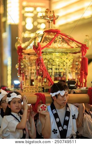 Osaka, Japan - July 23, 2018: Young Men And Women Carry A Portable Shrine Through Streets During Hea