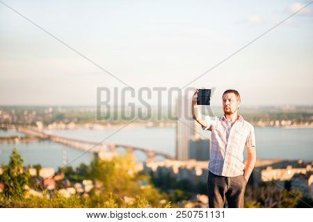 A Man In A Shirt And Trousers Takes Pictures Of Himself And Nature On The Phone. Portrait Of A Man I