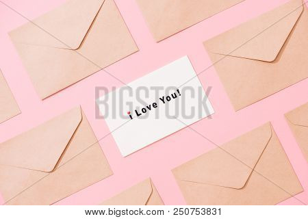Frame From Envelopes And Postcard On Pink Table Top View. Words I Love You. Valentine Concept. Flat