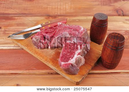 savory: red raw beef meat steak on wooden cutting board prepared for roasting