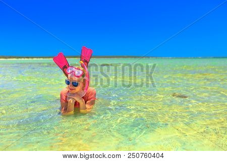 Caucasian Young Woman With Snorkeling Wetsuit, Mask And Fins In Pink And Peach Color, Sunbathing In 