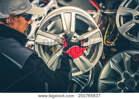 Buying New Alloy Wheels And Seasonal Tires Change Concept Photo. Caucasian Car Service Worker With L