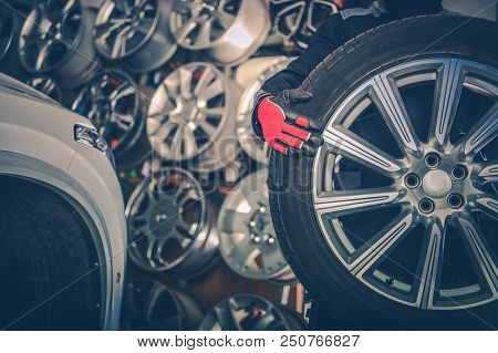 Picking New Alloy Wheels. Car Service Mechanic With Large Sport Utility Vehicle Wheel.