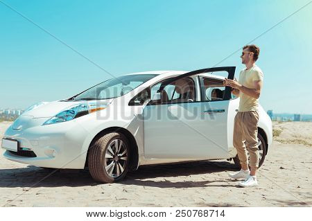 Fancy Car. Stylish Man Wearing Beige Trousers And Light Yellow Shirt Standing Near His New Fancy Car