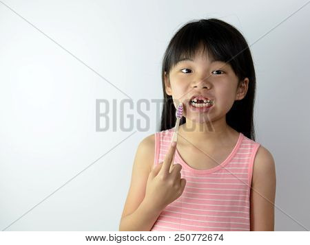 Little Asian Girl Without Front Teeth Holding A Tooth Brush